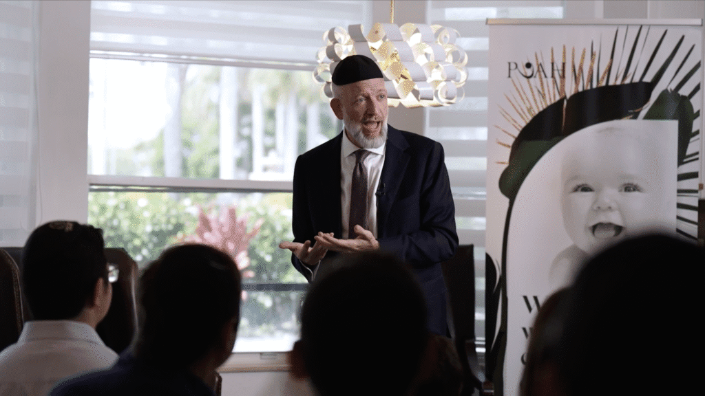 Video still of a speaker presenting at a community event
