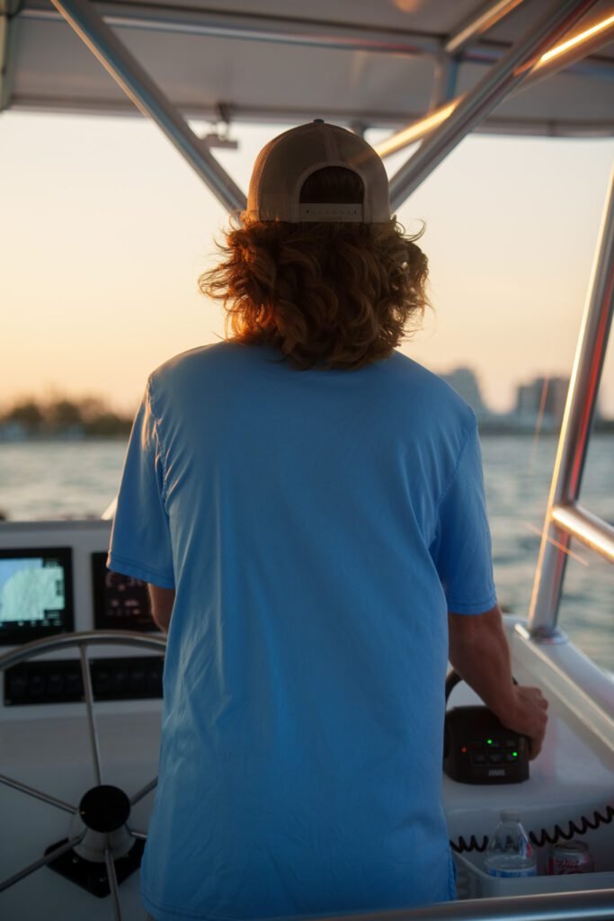 Sea Rocket captain at the helm at sunset with one hand on the throttle and the Fort Lauderdale waterway ahead