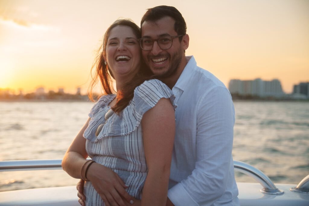 Couple embracing at the bow of the Sea Rocket sunset cruise as the sun drops behind the Fort Lauderdale waterfront