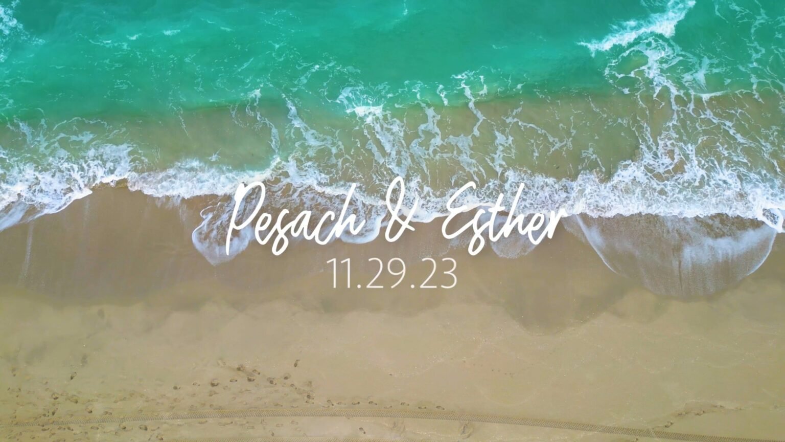 Overhead view of turquoise surf meeting sand with a couple's names and date in script