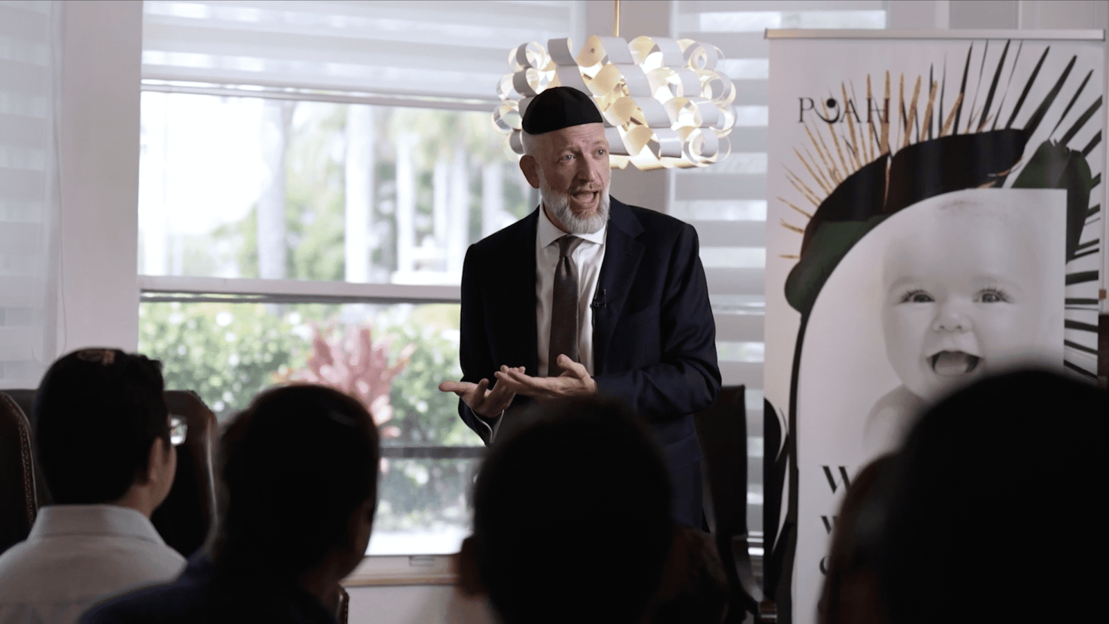 Video still of a speaker presenting at a community event