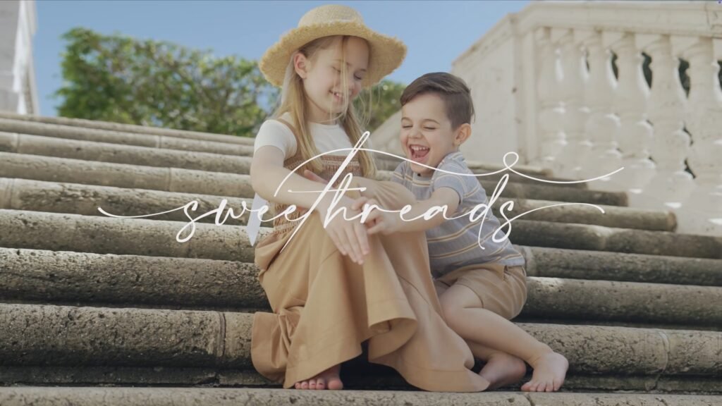Girl in a straw hat and laughing boy sitting on stone steps under handwritten script text