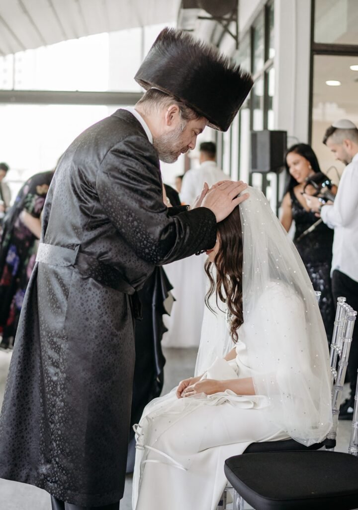 Zoli and Chava's bedeken, a man in a shtreimel blessing the seated bride