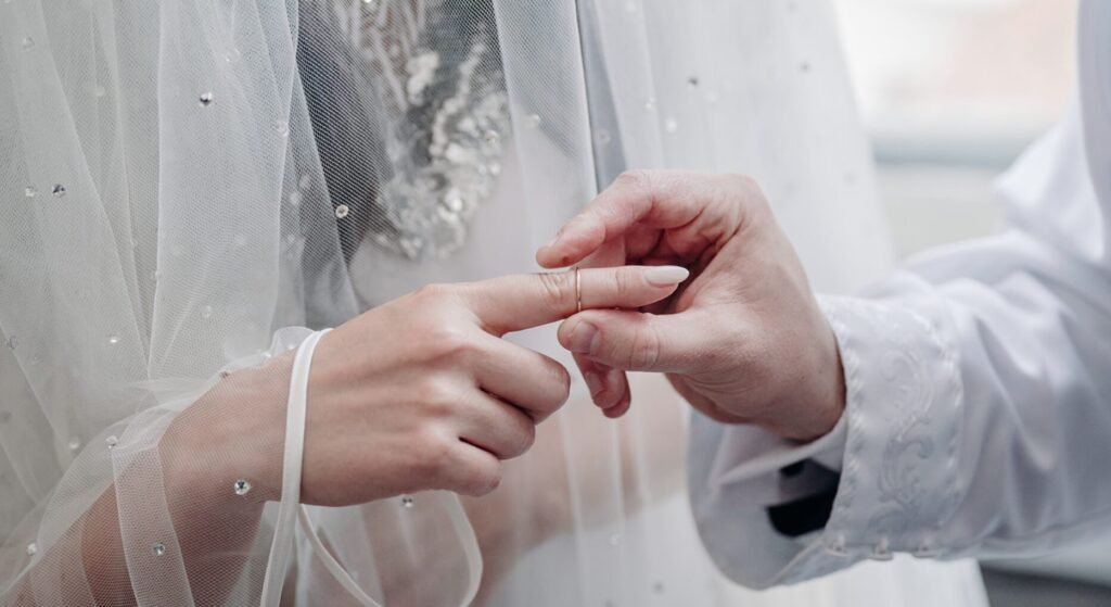 Zoli and Chava exchanging rings, her hand under a crystal-dotted veil