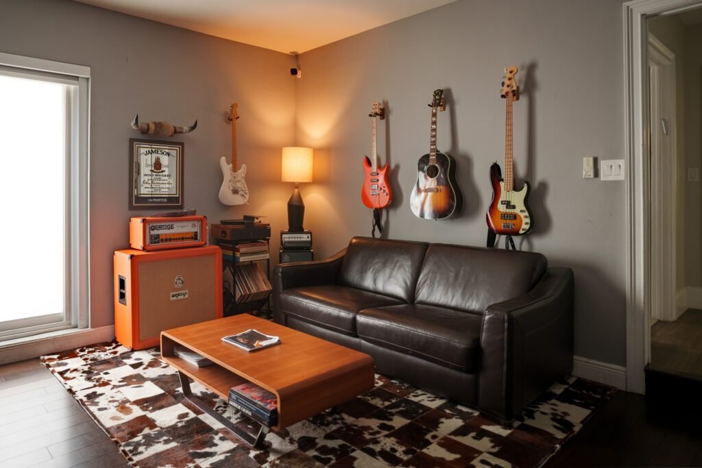 Living room with five guitars on the wall, leather sofa, amplifier and cowhide rug