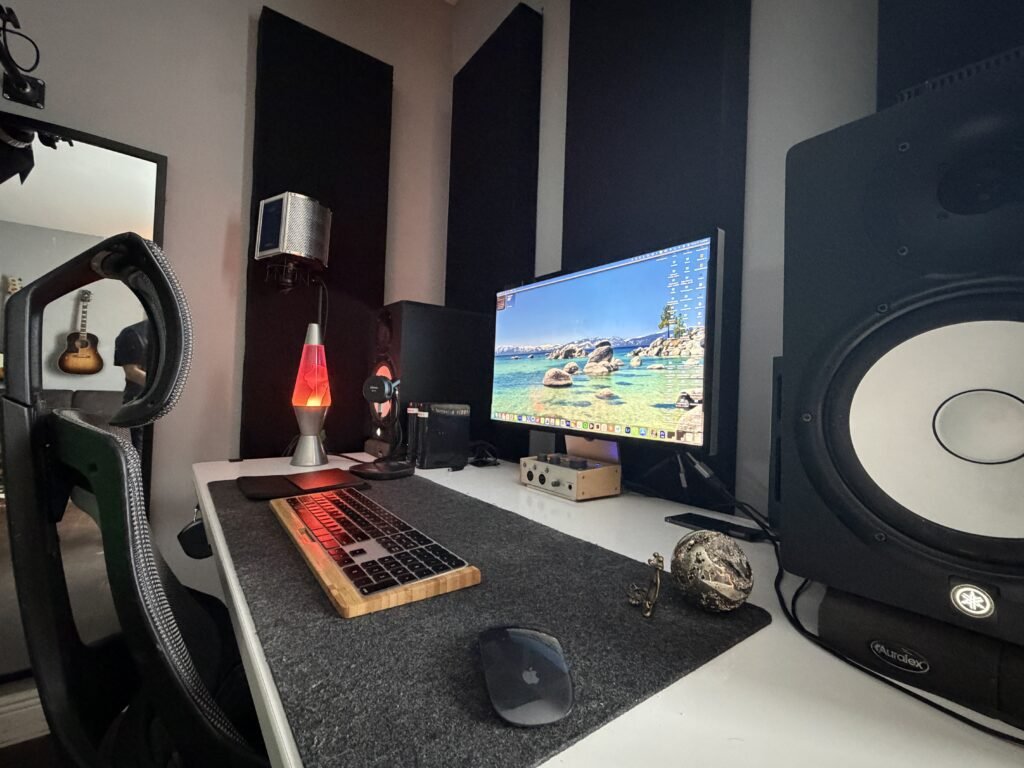 Desk with a monitor, mechanical keyboard, lava lamp and a large studio speaker