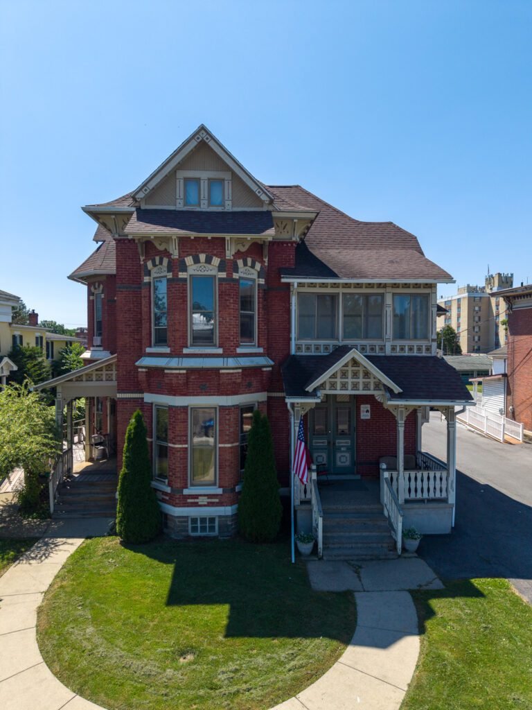 Red brick Victorian house in Penn Yan with a covered porch, bay window and American flag