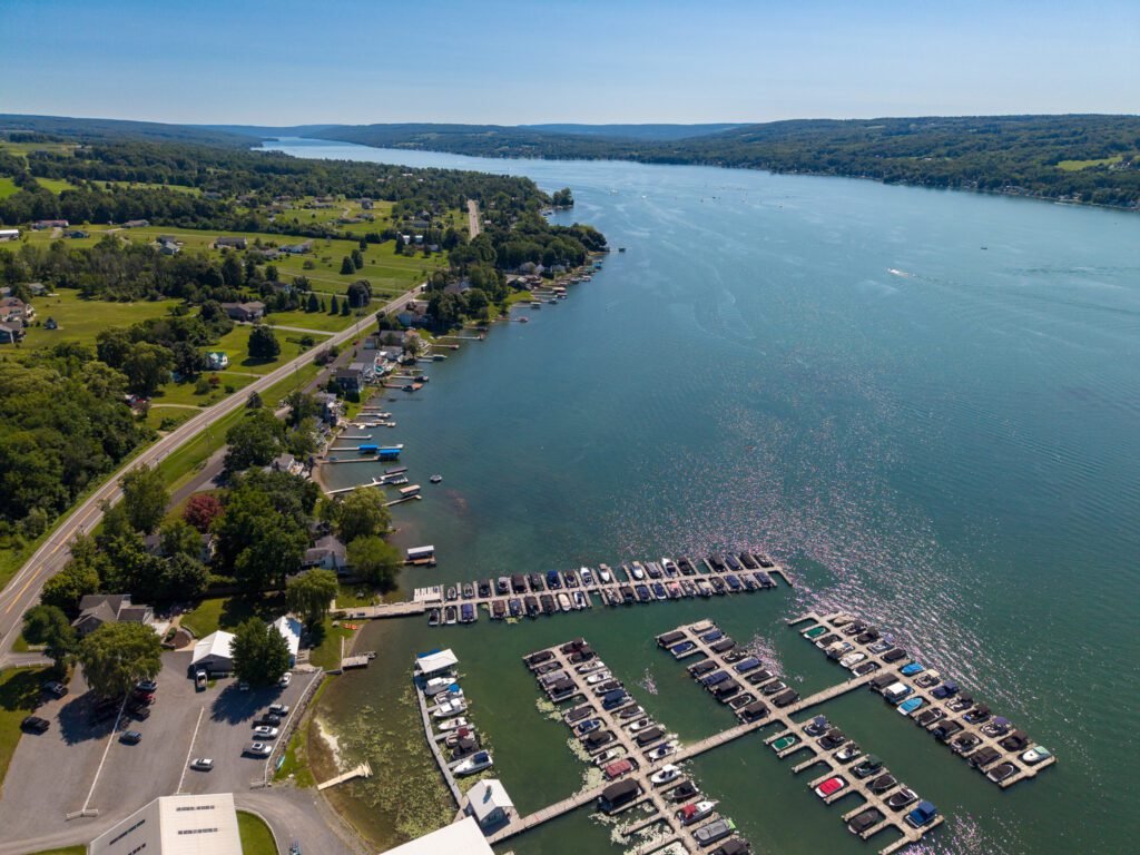 Aerial view of a Finger Lakes marina with rows of docked boats and the lake stretching to the horizon