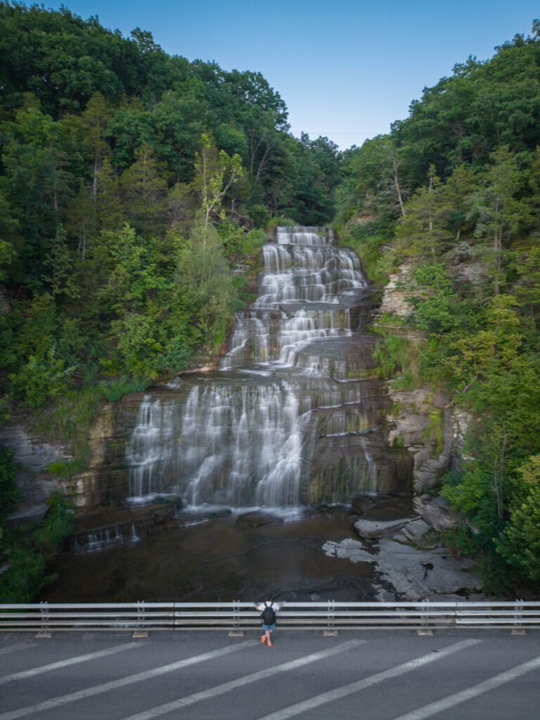 Aerial view of Hector Falls dropping in wide tiers beside the highway with a person at the guardrail
