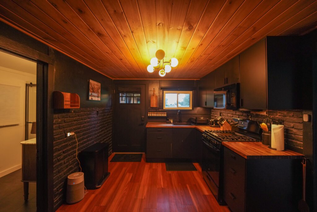 Kitchen with black brick walls, butcher-block counters and a cedar plank ceiling
