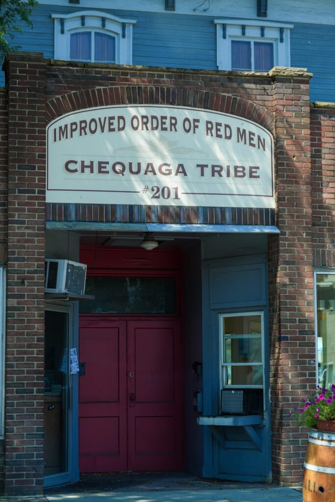 Painted sign reading Improved Order of Red Men, Chequaga Tribe 201, above the red doors of a lodge in Montour Falls
