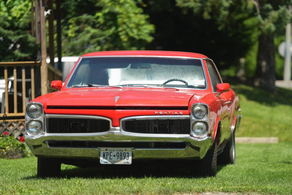 Front view of a red 1960s Pontiac parked on a lawn in the Finger Lakes countryside