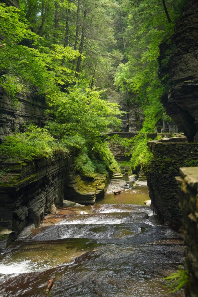 Shallow rapids running over flat rock in the gorge at Watkins Glen with the stone walkway alongside
