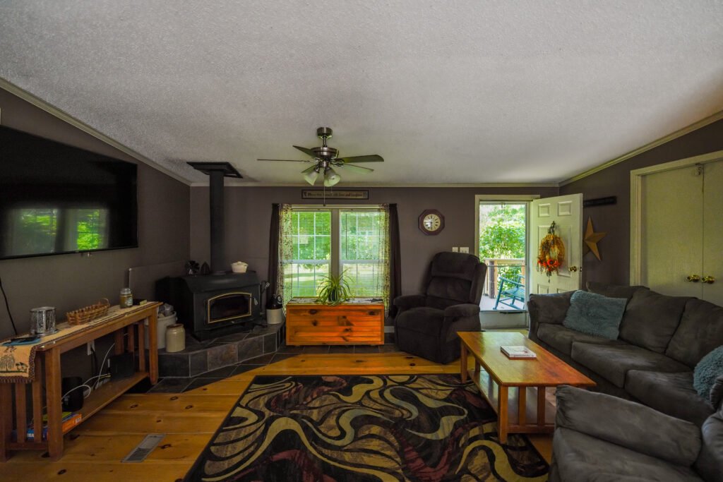 Living room with a wood stove, patterned rug and an open door to the deck