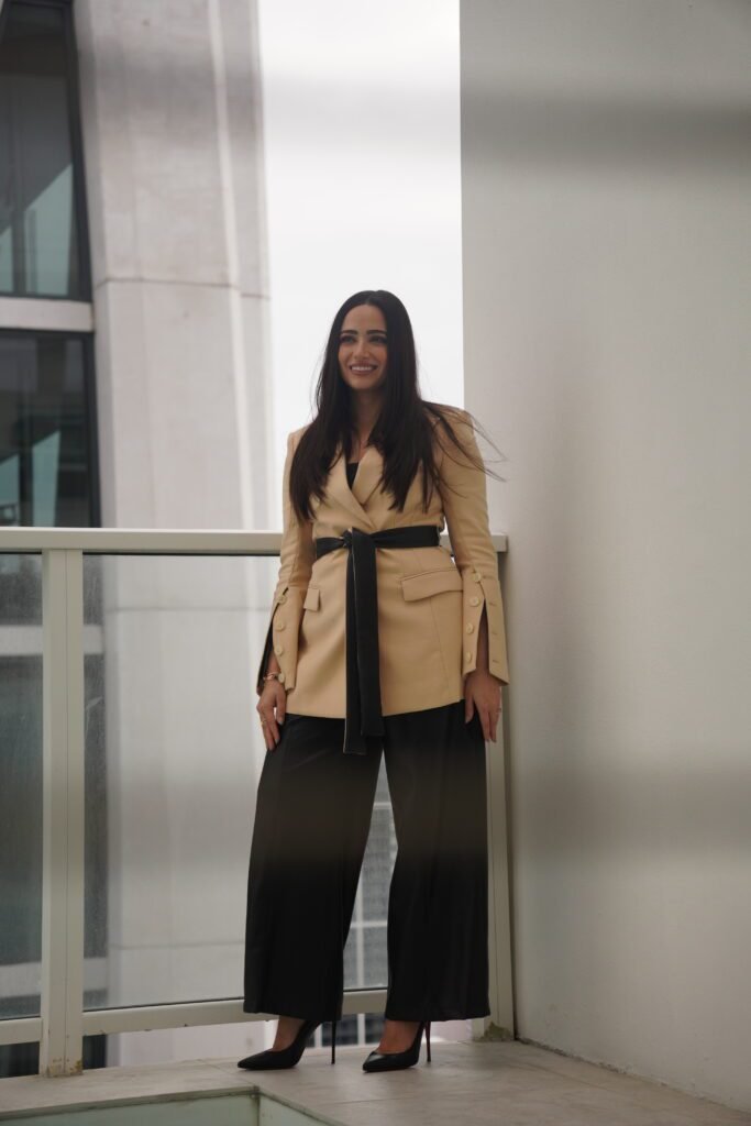 Chava Feigen standing on a high floor terrace at Ten Museum Park in a tan blazer, filmed for a Miami real estate video