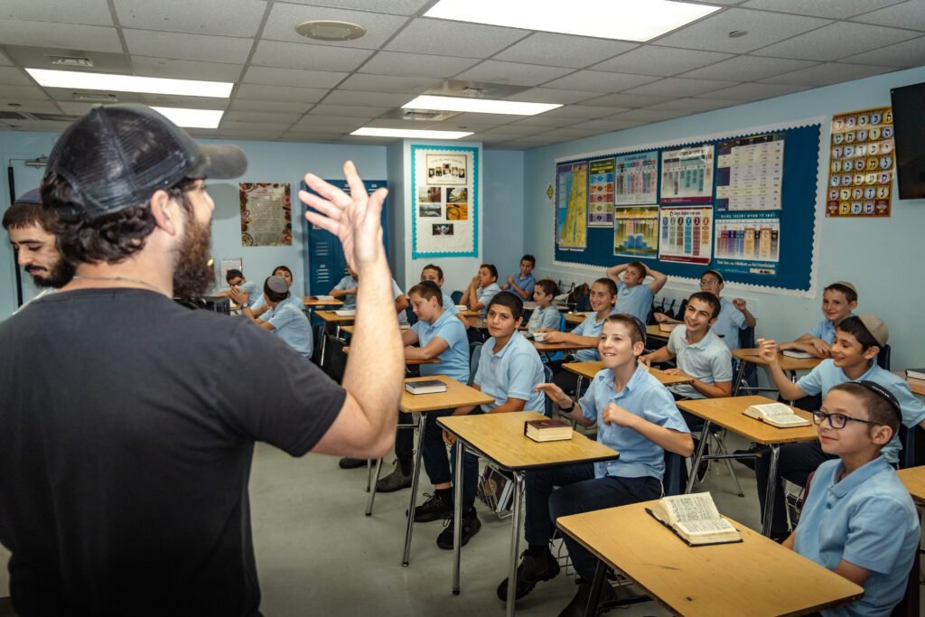 The director in a backwards cap directing a classroom of boys during a take for the Gift to the Rebbe music video at LEC