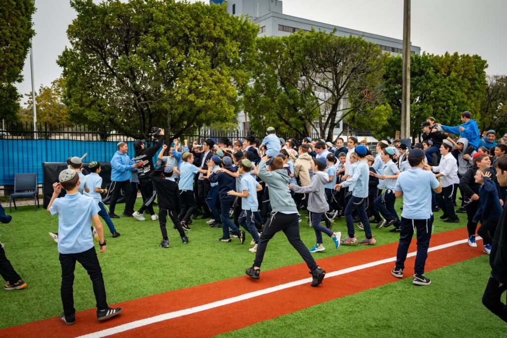 Students running across the school field during the all-school scene of the Gift to the Rebbe music video