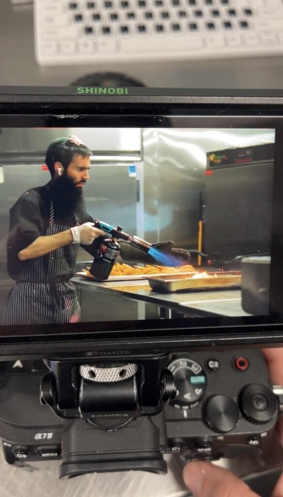 Camera monitor showing a chef finishing a dish with a blowtorch during the Chef Sabrina Mancin trailer shoot