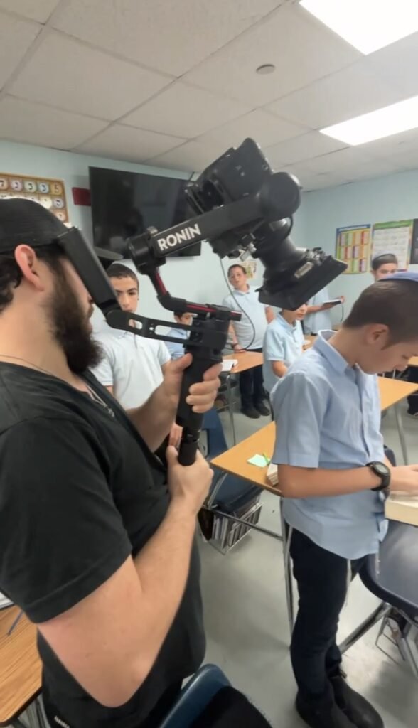 Operator with a gimbal filming boys at their desks in an LEC classroom
