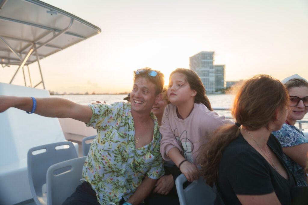 Guest in a floral shirt taking a selfie with a laughing young girl aboard the Sea Rocket sunset cruise at golden hour