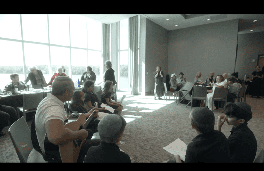 Children and adults gathered for a sing-along beside the bay-facing windows, one man playing guitar