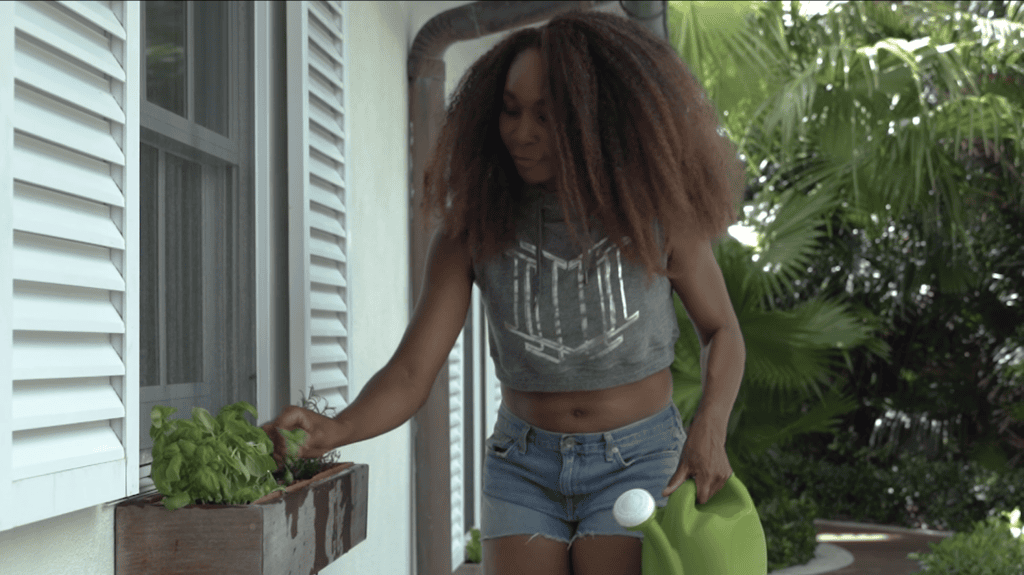 Venus Williams picking basil from a window planter box, a watering can in her other hand