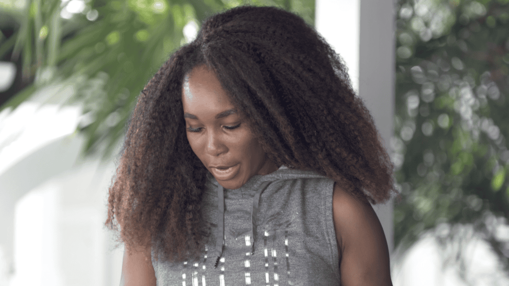 Venus Williams looking down and laughing mid-conversation in a grey hooded top