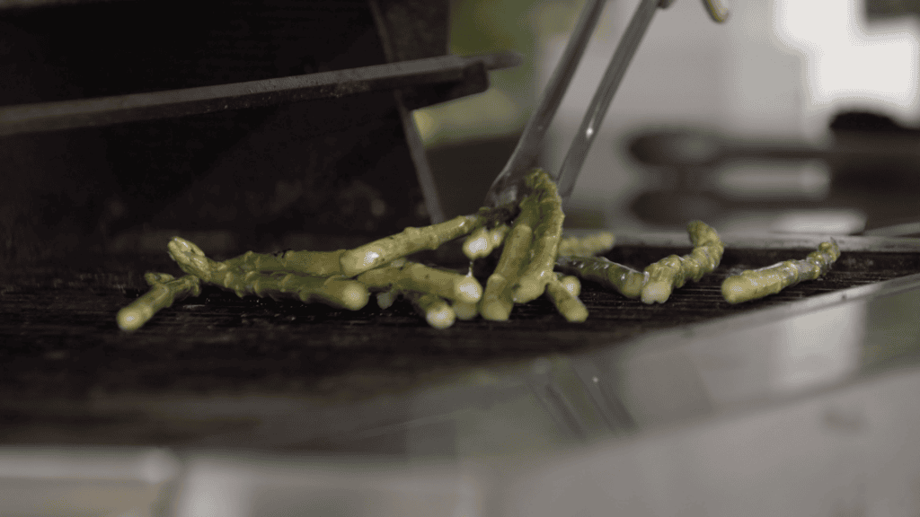 Asparagus spears turned with tongs on a hot grill
