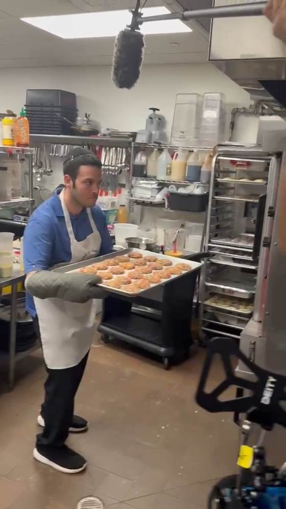 Boom microphone overhead in the Friendship Bakery kitchen while the team works with a tray of rugelach